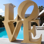 love en métal doré devant une piscine d'une villa de nice