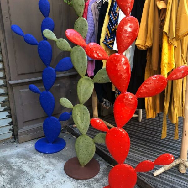 cactus de différente couleurs en métal devant un magasin