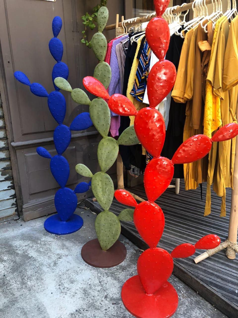 cactus de différente couleurs en métal devant un magasin