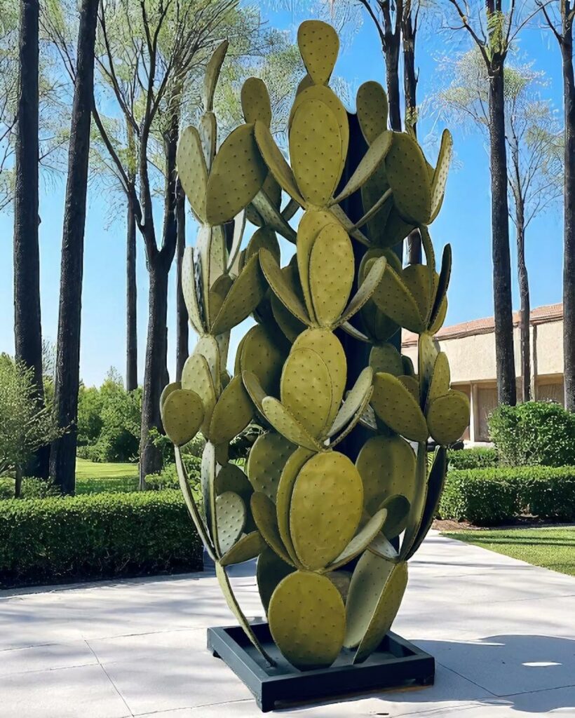 Grande sculpture de cactus en métal sur terrasse avec vue arborée