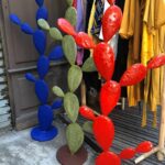 Sculptures en métal colorées en forme de cactus rouge, bleu et vert devant une boutique de vêtements