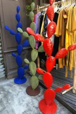 Sculptures en métal colorées en forme de cactus rouge, bleu et vert devant une boutique de vêtements