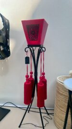 Détail ajouré d’une lampe en métal noir et cire rouge, motif oriental lumineux