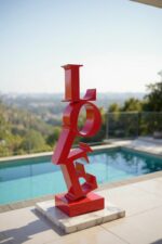 Sculpture rouge “LOVE” placée près d’une piscine avec vue panoramique.