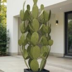 Grande sculpture verte en forme de cactus sur une terrasse moderne.