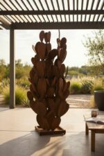 Sculpture en métal rouille représentant un cactus, installée sur une terrasse ensoleillée