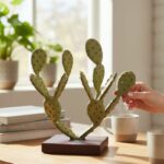Petite sculpture en métal vert en forme de cactus posée sur un bureau lumineux