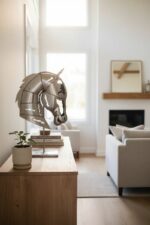 Sculpture en métal représentant une tête de cheval posée sur un meuble dans un salon lumineux