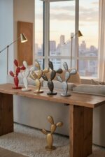 Série de sculptures en métal colorées en forme de cactus sur une table en bois, dans un salon moderne