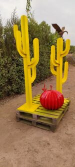 Sculpture de cactus en métal jaune avec boule rouge décorative, installation artistique pour jardin ou terrasse